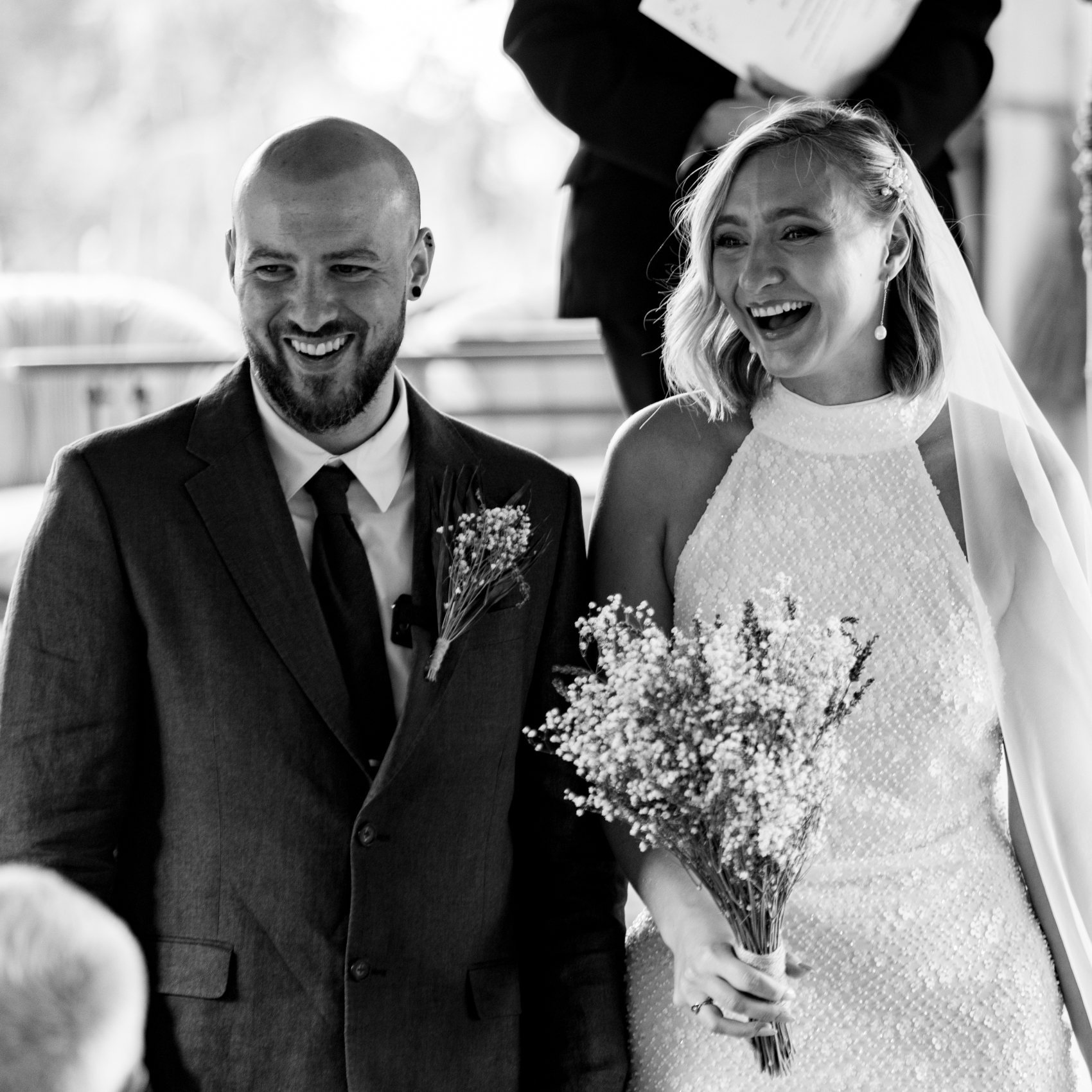 Black and white photograph of a bride and groom laughing during their wedding ceremony